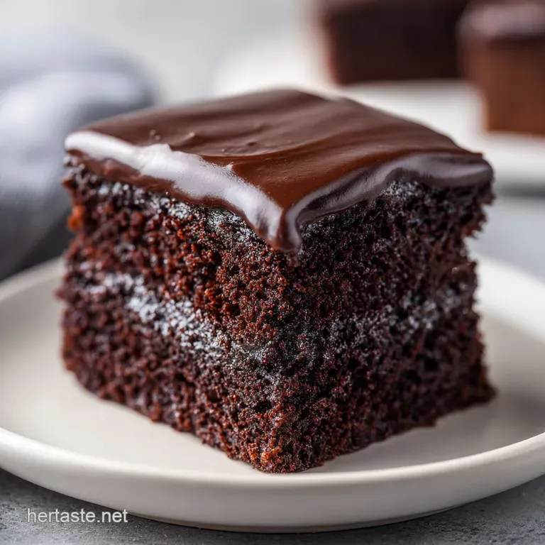 A rectangular slice of dark chocolate cake with creamy frosting and crunchy pecan bits on a minimalist white plate.